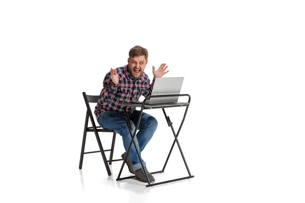 Full-length portrait of man screaming into laptop screen, having online communication isolated over white background — Foto Stock