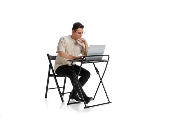 Full-length portrait of young boy sitting in fron of laptop and having online lesson isolated over white background — Foto Stock