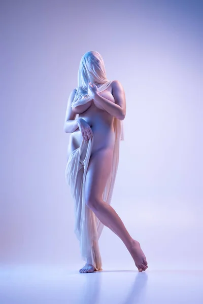 네온 조명을 받은 보라색 배경 위로 나체로 나체로 나체로 포즈를 취하고 있는 투명 베일을 쓴 젊은 여성의 사진 — 스톡 사진