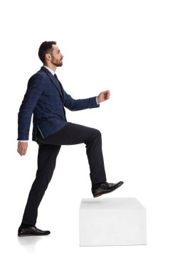 Full-length portrait of businessman, office worker making steps symbolizing personal growth isolated over white background