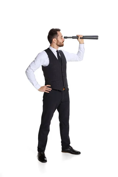 Full-length portrait of young man, employee looking in telescope isolated over white background — Zdjęcie stockowe