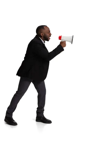 Full-length portrait of angry man, office worker shouting in megaphone isolated over white background — Stockfoto