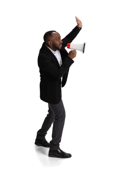 Full-length portrait of young man, office worker shouting in megaphone isolated over white background — Stockfoto