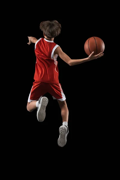 Full-length studio shot van basketbalspeler in beweging, springen en gooien bal geïsoleerd over zwarte achtergrond. Achteraanzicht — Stockfoto