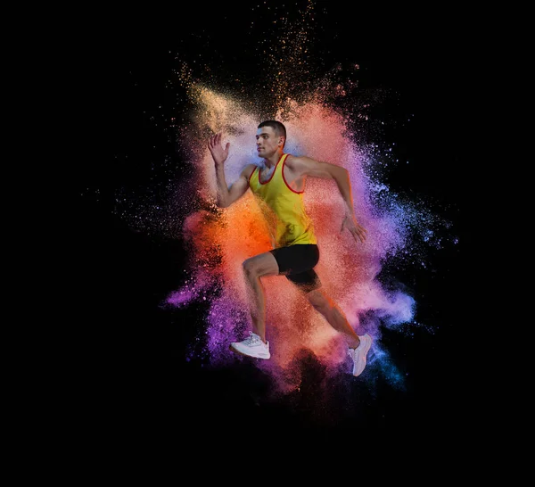 大学生活。男人，专业跑步运动员训练隔离在黑色背景与彩色粉末爆炸 — 图库照片