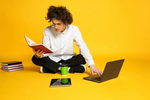 Retrato de jovem, estudante concentrado estudando, preparando-se para exames, lendo isolado sobre fundo estúdio amarelo — Fotografia de Stock