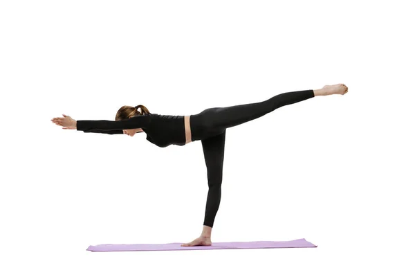 Ritratto di giovane donna in tuta nera confortevole formazione, facendo esercizi di yoga isolati su sfondo bianco studio — Foto Stock