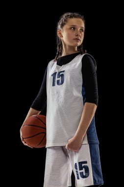Genç kız portresi, üniformalı basketbolcu siyah stüdyo arka planında yalnız poz veriyor. Spor eğitimi.