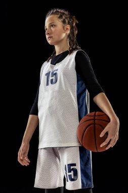 Genç kız portresi, üniformalı basketbolcu siyah stüdyo arka planında yalnız poz veriyor. Takım lideri