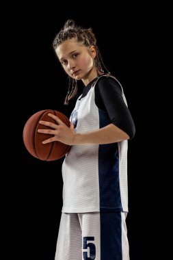 Genç kız portresi, üniformalı basketbolcu siyah stüdyo arka planında yalnız poz veriyor.