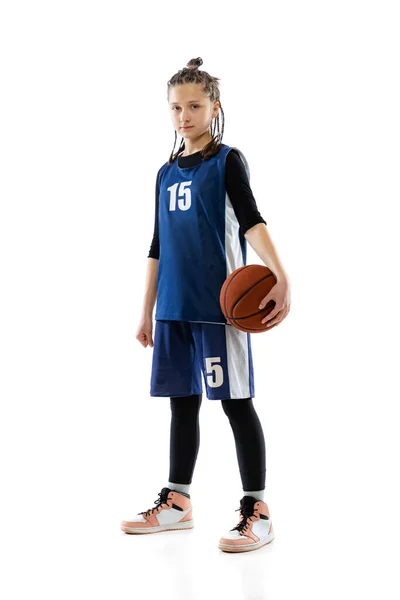 Full-length portrait of teen girl, active sportsman posing in uniform of basketball player isolated over white studio background — Stockfoto