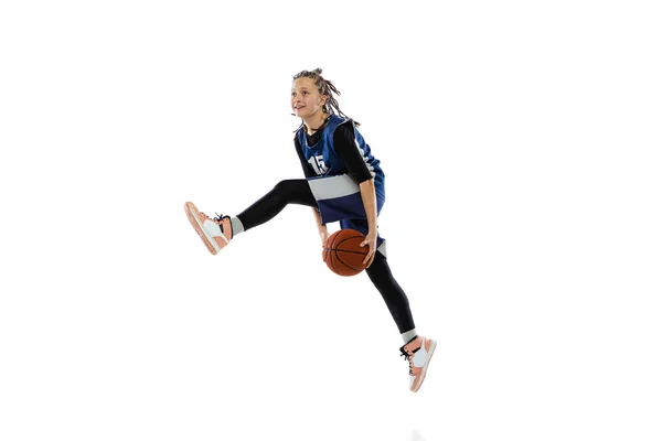 Dynamic portrait of teen girl, basketball player training, jumping with ball isolated over white studio background — стоковое фото