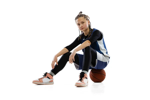 Πορτρέτο της νεαρής κοπέλας, μπασκετμπολίστας κάθεται στην μπάλα, ανάπαυσης μετά από ενεργό παιχνίδι απομονώνονται σε λευκό φόντο στούντιο — Φωτογραφία Αρχείου