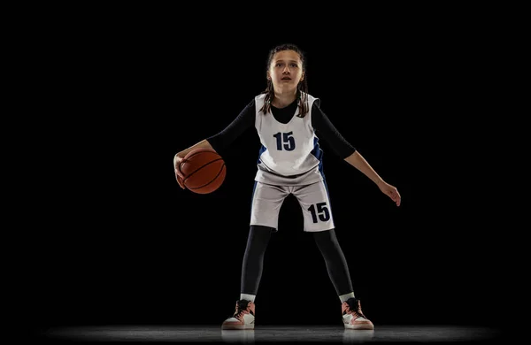 Πορτρέτο της έφηβης, μπασκετμπολίστας σε κίνηση, ντρίμπλα μπάλα απομονωμένη σε μαύρο φόντο στούντιο. Χτυπήστε τον αμυντικό — Φωτογραφία Αρχείου