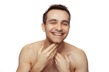 Çekici, gülümseyen, kusursuz tıraşlı yüzü olan genç bir adamın portresi beyaz stüdyo arka planında izole edilmiş poz veriyor.