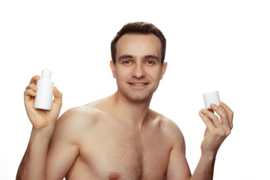 Beyaz arka planda izole edilmiş deri tahrişinden kaçınmak için tıraş olduktan sonra yüz losyonu süren genç bir adamın portresi.