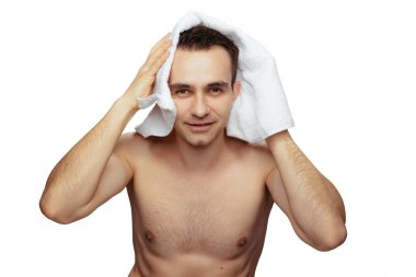 Duştan sonra genç bir adamın portresi, beyaz arka planda yıkandıktan sonra saçlarını havluyla kurutmak.