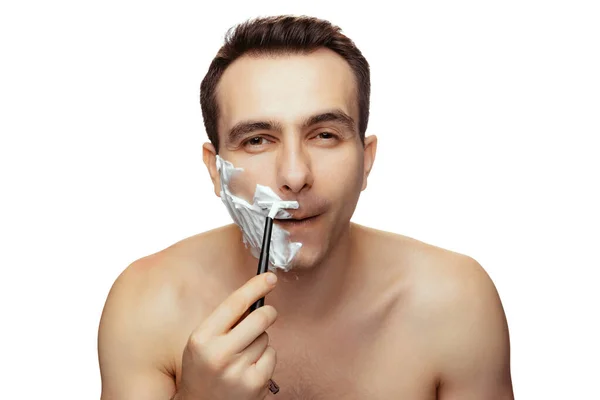 Portrait d'homme avec demi-visage recouvert de crème à raser, rasage avec rasoir isolé sur fond blanc studio. — Photo