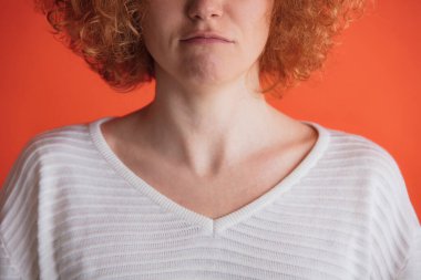 Kırmızı stüdyo arka planında izole edilmiş beyaz tişörtle poz veren kızıl saçlı kadın görüntüsü. Yoğunlaşmış görünüyor.