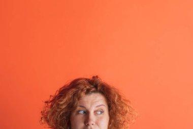 Kızıl saçlı kadının yarım yüzlü portresi. Kırmızı stüdyo arka planında izole edilmiş. Sağa bak.