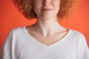 Kırmızı stüdyo arka planında izole edilmiş beyaz tişörtle poz veren kızıl saçlı kadın görüntüsü.