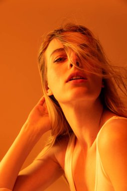 Portakal rengi stüdyo arka planında izole edilmiş güzel bir kızın portresi.