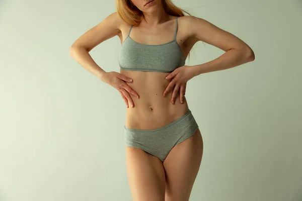 Cropped image of slim female body in comfortable underwear isolated over grey studio background. Perfect shape — Foto Stock