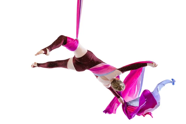 Portrait of young woman, air gymnast training, performing isolated over white studio background. Fascinating performance — Stock Fotó