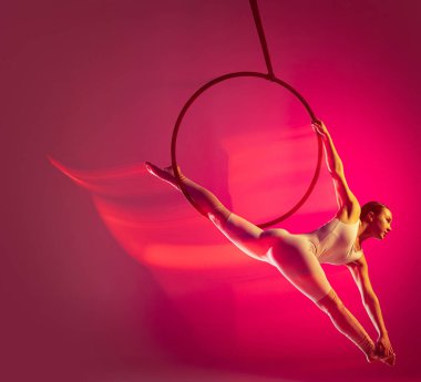 One young girl, professional air gymnast training, performing isolated over pink background with mixed lights effect. On a twine