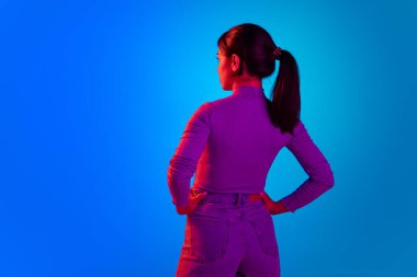 Arka planda, neon ışıklı arka planda soyutlanmış bir şekilde poz veren genç bir kızın portresi.