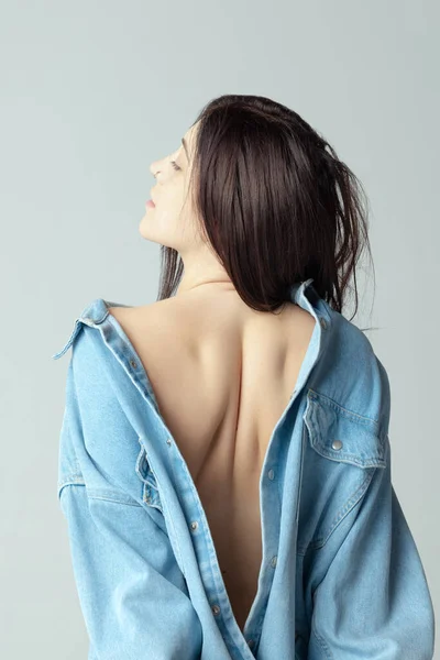 Beautiful shape of female back. One beautiful woman posing in shirt isolated over grey studio background —  Fotos de Stock
