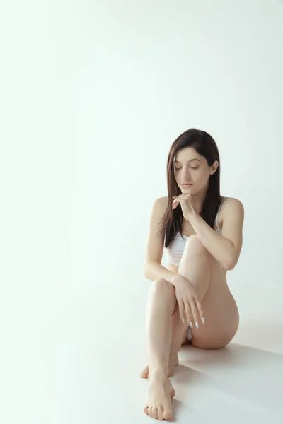 Portrait of young tender woman sitting, posing in underwear isolated over grey studio background. Femininity — Foto de Stock