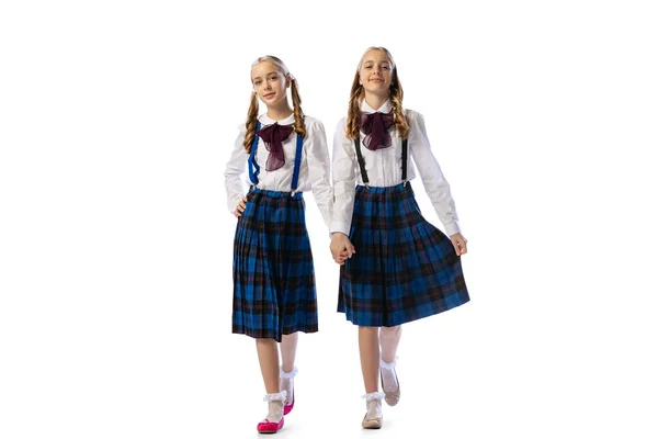 Portrait of two little beautiful girls, twins in stylish dresses posing isolated over white studio background — Stock Photo, Image