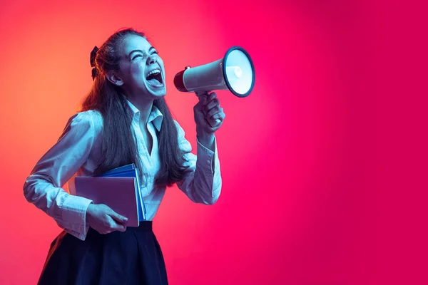 Retrato de menina emotiva jovem, estudante gritando em megafone isolado sobre fundo de estúdio rosa em luz de néon — Fotografia de Stock