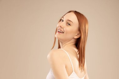 Doğallık. Gri stüdyo arka planında izole edilmiş, gülümseyen güzel kızıl saçlı kızın portresi. Doğal güzellik kavramı, vücut ve cilt bakımı, sağlık, spa, sağlık, kozmetik, reklam
