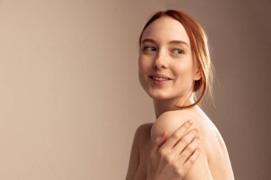Gri stüdyo arka planında izole edilmiş güzel kızıl saçlı kızın portresi. Dikkatli, sakin bak. Doğal güzellik kavramı, vücut ve cilt bakımı, sağlık, spa, sağlık, kozmetik, reklam