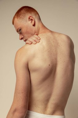 Gri stüdyo arka planında izole edilmiş kaslı erkek portresi. İç çamaşırlarıyla poz veren bir model. Erkeklik. Erkek sağlığı, güzellik, vücut ve cilt bakımı, spor anlayışı. Vücut sanatı