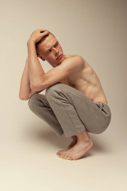 Gri stüdyo arka planında izole edilmiş pantolonsuz poz veren genç, kızıl saçlı bir adamın portresi. Ciddi bir bakış. Erkek güzelliği, moda, erkek sağlığı, sağlık, zindelik kavramı