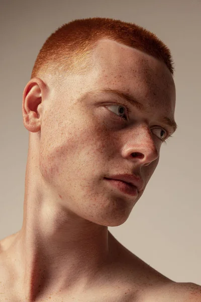 스튜디오 배경에 주근깨가 잘생긴 머리젊은 남자의 광대뼈가 늘어져 남성적 아름다움 — 스톡 사진