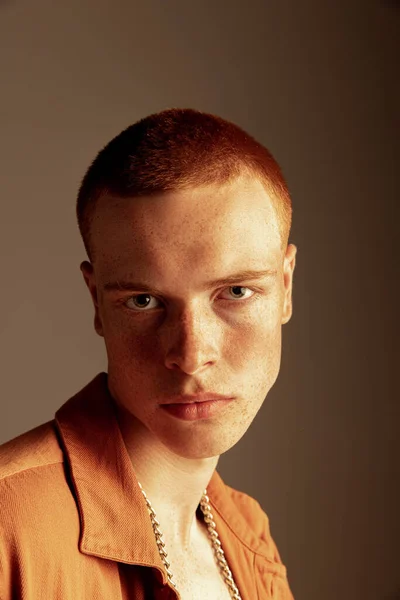 年轻英俊的红头发男子的特写画像 他的雀斑在棕色背景下呈孤立的卵形 有明显的颧骨时尚 身体美学 男人健康的概念 — 图库照片