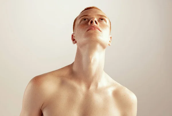 年轻红头发男子的画像 穿着无袖上衣 在灰色的工作室背景上向上望 男性健康 生活方式 身体和皮肤护理的概念 有雀斑的模型 — 图库照片