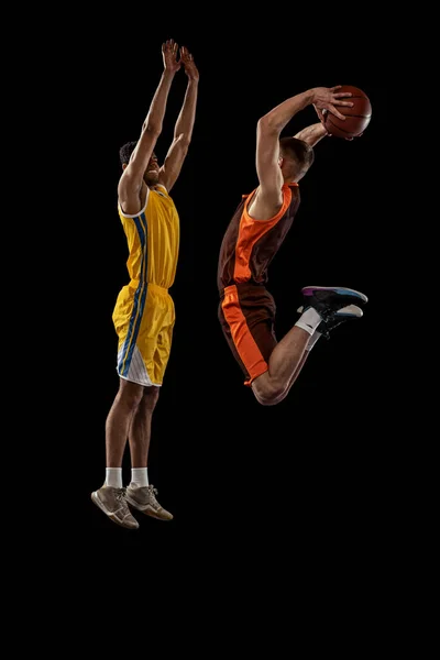 2人の若い男性 運動中のプロのバスケットボール選手の肖像画 黒のスタジオの背景に孤立したボールでジャンプします スポーツ チームゲーム アクション アクティブライフスタイル 広告の概念 — ストック写真