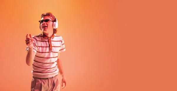Portret Młodego Człowieka Słuchającego Muzyki Słuchawkach Tańczącego Pomarańczowym Tle Studia — Zdjęcie stockowe