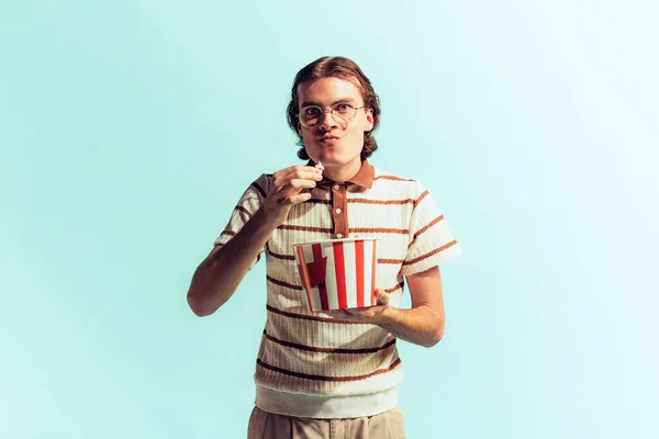 Portret Młodego Mężczyzny Pozującego Koszykiem Popcornu Odizolowanym Tle Jasnoniebieskiego Studia — Zdjęcie stockowe
