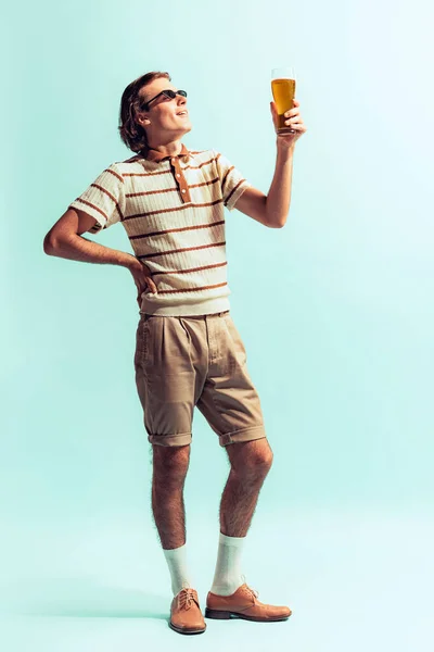 カジュアルな服装で若い男の肖像は ライトブルーのスタジオの背景に孤立ポーズクールなビールを飲む リラックスした気分 ファッション ライフスタイル 感情の概念 広告のコピースペース — ストック写真