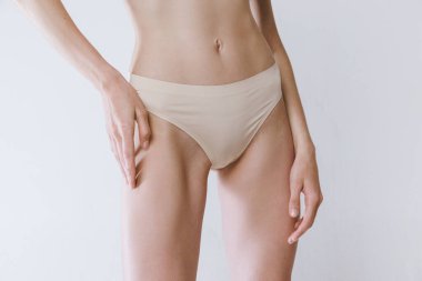 İnce kadın vücudu, göbeği, gri stüdyo arka planında izole edilmiş iç çamaşırlı kalçaları. Kadın sağlık hizmetleri. Güzellik, vücut ve cilt bakımı, sağlık, kaplıca, kozmetik, reklam