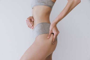 Gri stüdyo arka planında izole edilmiş pamuk külotlu kadın kalçalarının kırpılmış görüntüsü. Anti-selülit tedavisi. Fitness, diyet. Güzellik, vücut ve cilt bakımı, sağlık, kaplıca, kozmetik, reklam