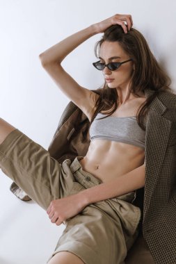 Gri stüdyo arka planında izole bir şekilde poz veren güzel, şık bir genç kızın portresi. Güzellik, moda, tarz, yaşam tarzı, vücut ve cilt bakımı, sağlık, kozmetik, reklam