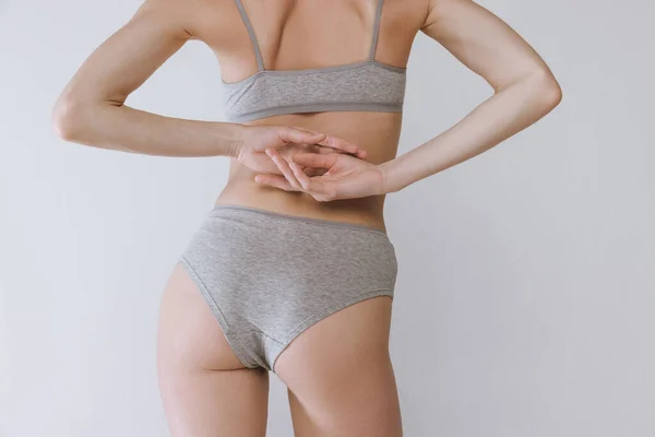 灰色のスタジオの背景に隔離された下着でスリムな女性の体 お尻の背面図 健康な体を保つこと ボディ スキンケア 化粧品 広告の概念 — ストック写真