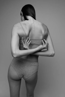 İç çamaşırlarıyla poz veren ince bir genç kadının yan görünümü. Siyah beyaz fotoğrafçılık. Eski estetik şekiller. Doğal güzellik kavramı, vücut ve cilt bakımı, kadınlık, kendini kabullenme, reklam